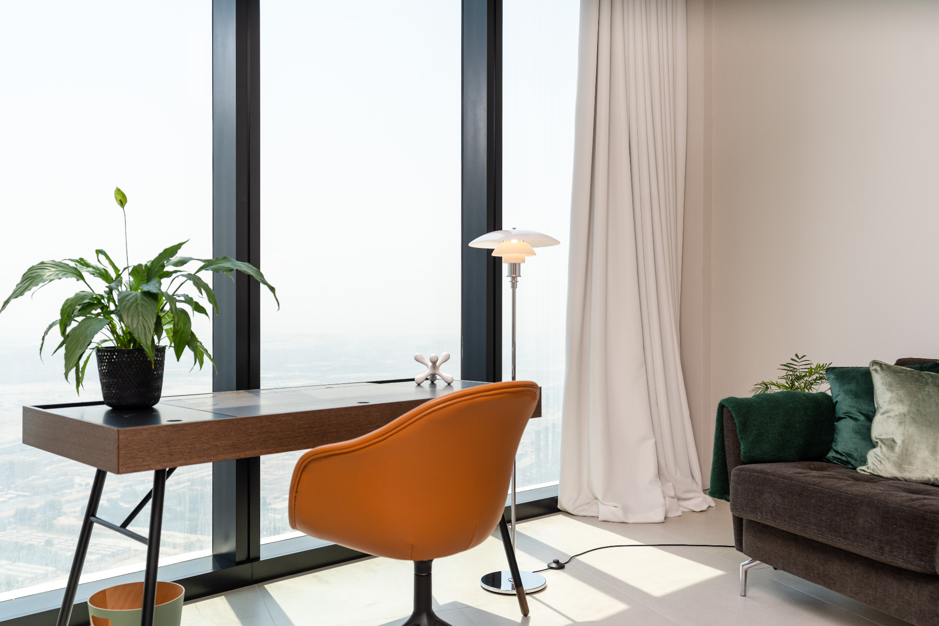 Home office corner with walnut writing desk, tan leather swivel chair and PH floor lamp against the skyline