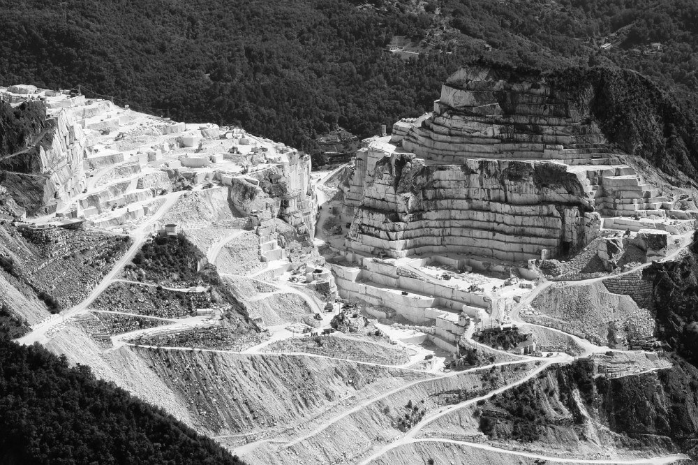 A marble quarry carved into geometric terraces of pale stone.